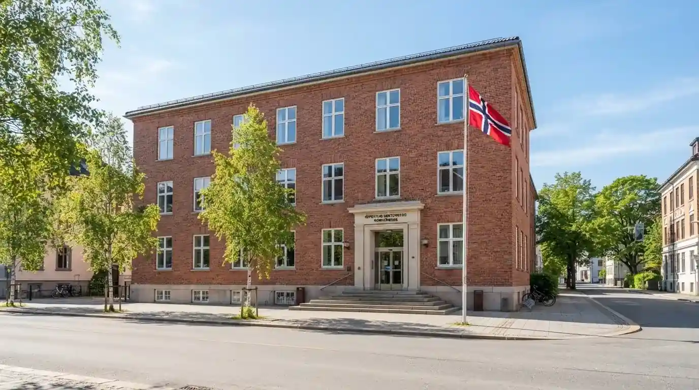 Offentlig kontorbygning i rødt murstein i en norsk by, med et flagg ved inngangen og blå himmel